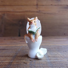 Mouse reading a book in the toilet as a small decoration