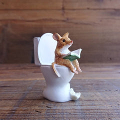 Mouse reading a book in the toilet as a small decoration